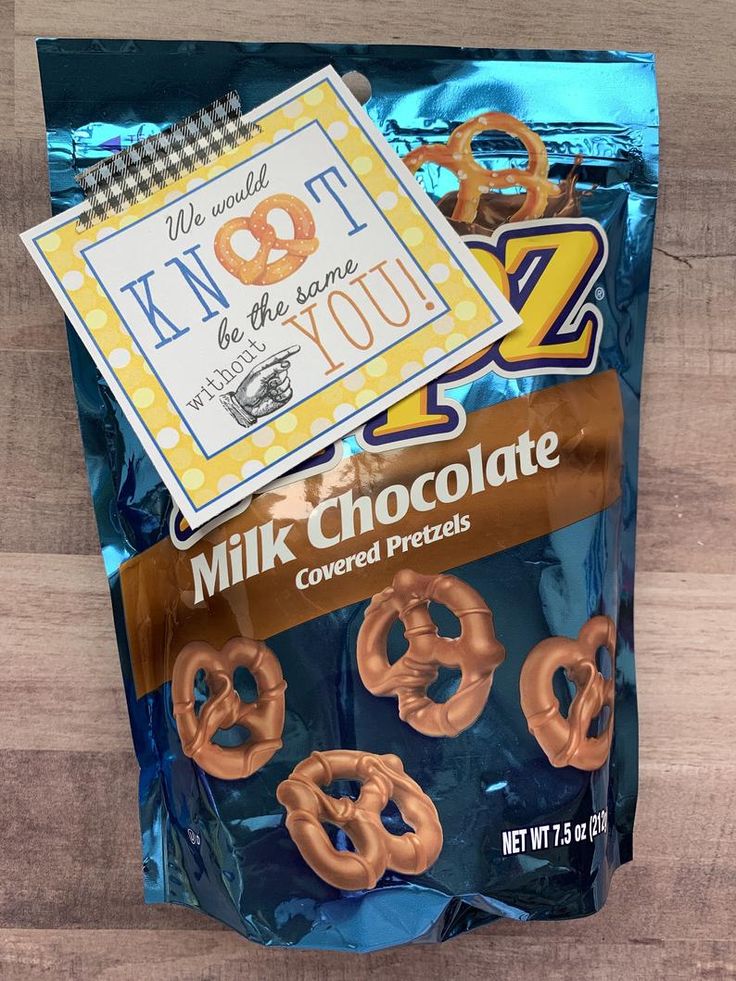 a bag of milk chocolate covered pretzels on top of a wooden table next to a sign