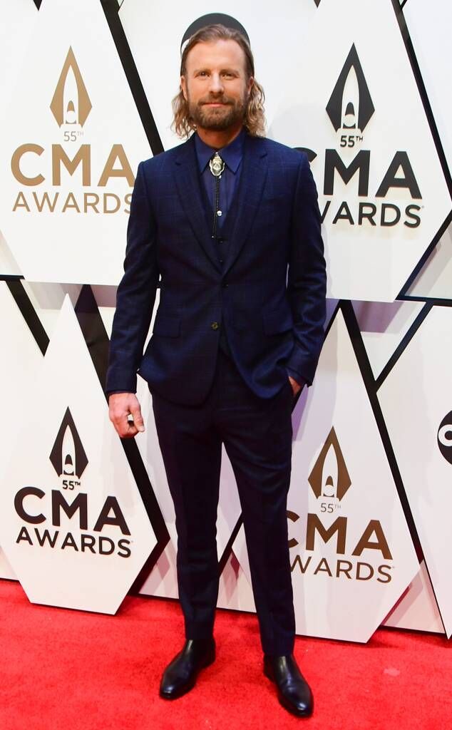 a man in a suit and tie standing on the red carpet at an awards event