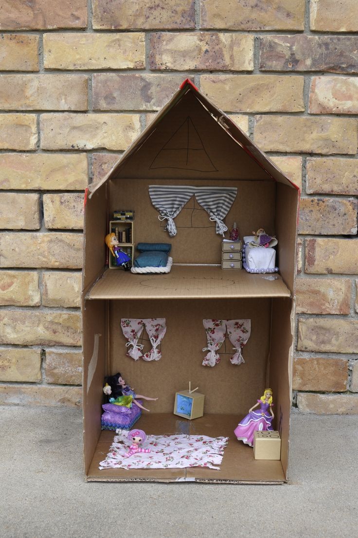 a cardboard doll house with clothes and accessories on the shelves in front of a brick wall