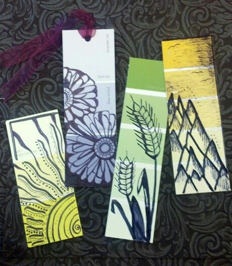 four bookmarks with different designs on them sitting on a black tablecloth covered surface