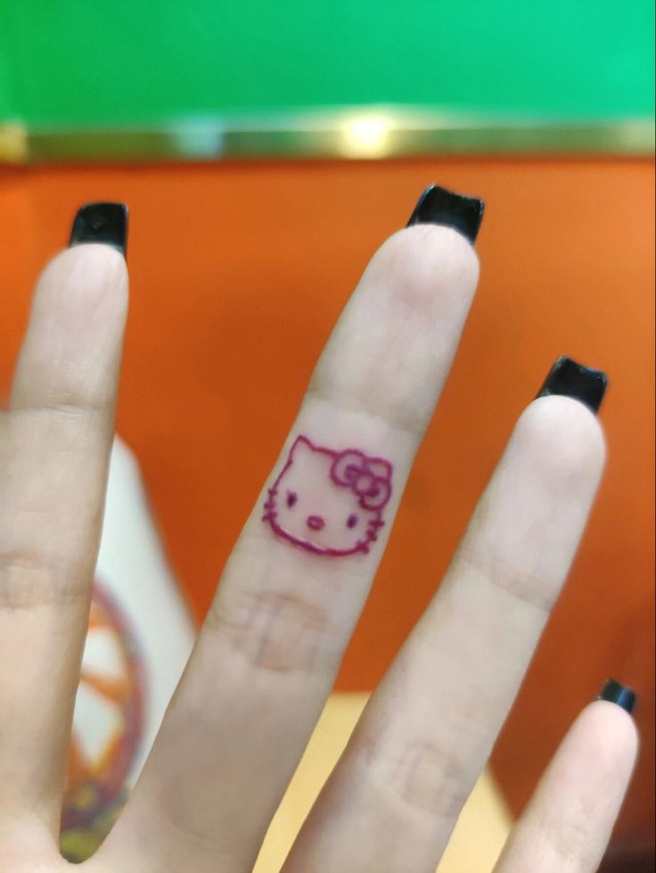 a hello kitty finger tattoo on someone's left hand