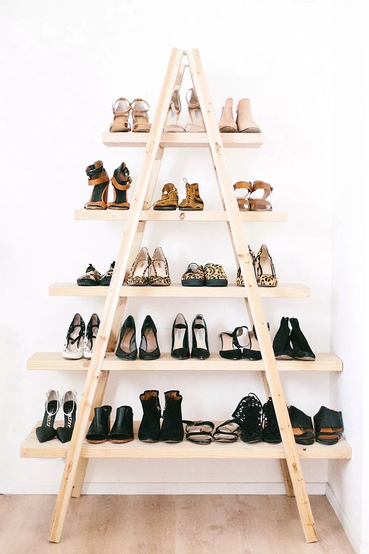 there is a ladder that has many pairs of shoes on it in front of a white wall