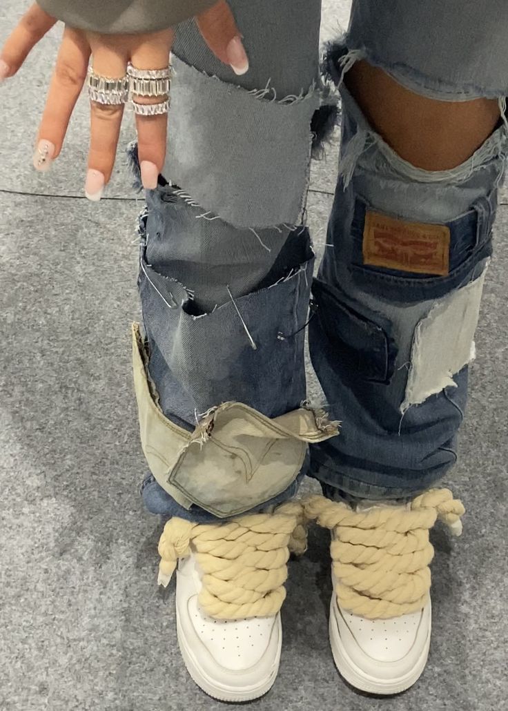 someone is holding their hand in the pocket of some ripped up jeans and shoes that have been tied together