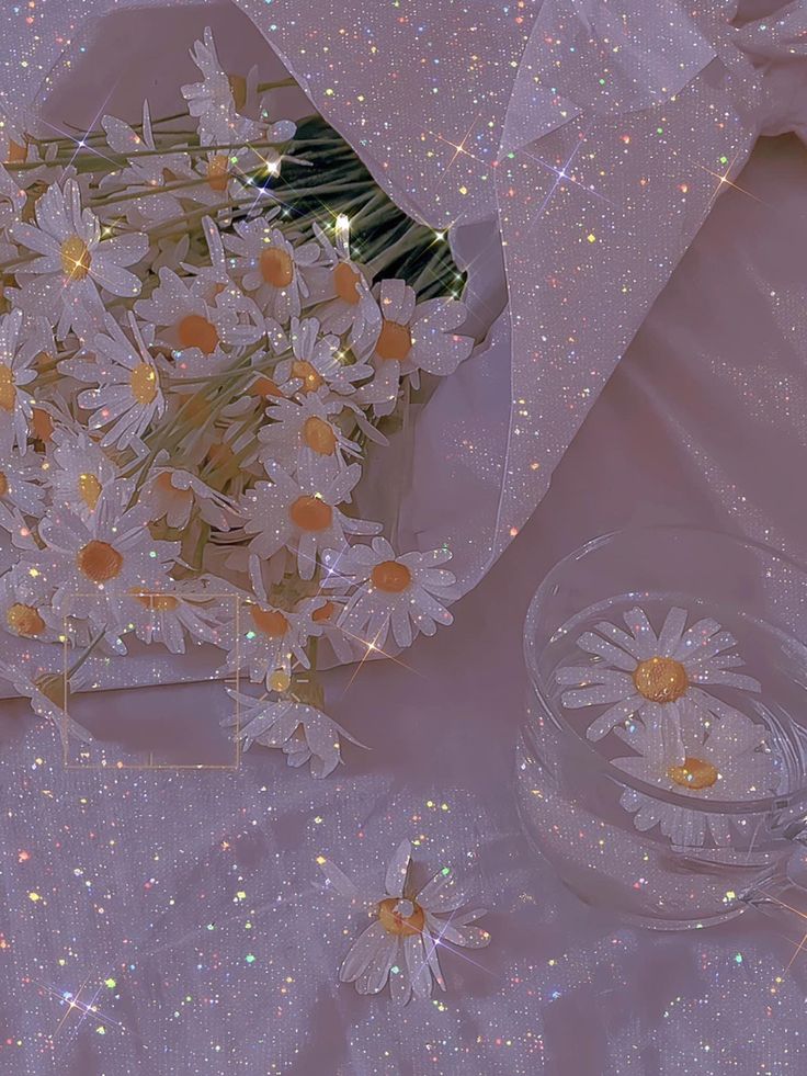 a bouquet of daisies sitting next to a glass bowl