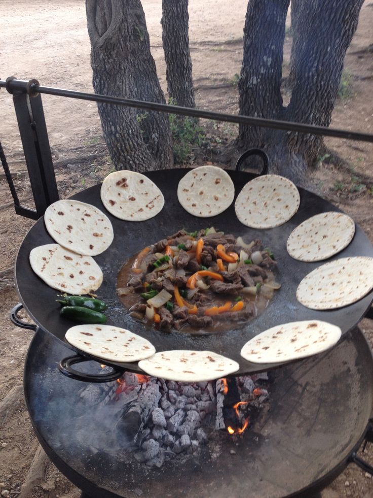 an outdoor grill with several different types of food cooking on the griddle and charcoal fire