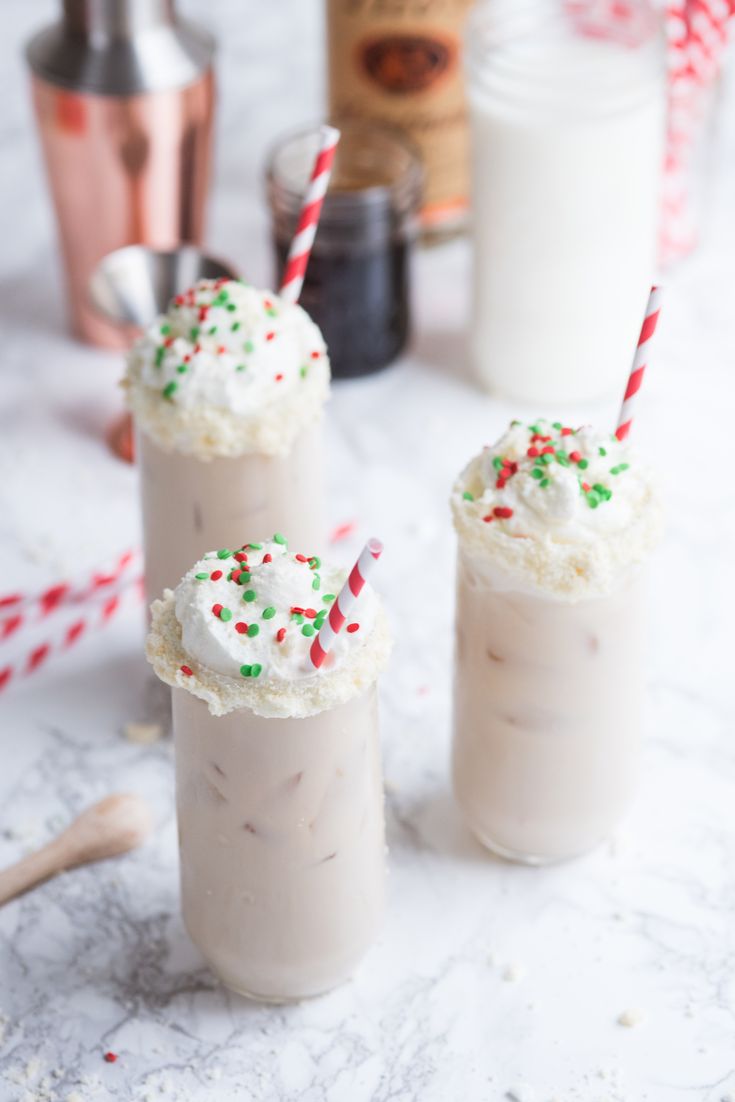 two drinks with whipped cream and sprinkles on the top are sitting next to each other