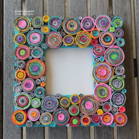 a photo frame made out of rolled up paper circles on a wooden table with a white board in the middle