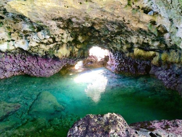 the inside of a cave with green water and rocks on either side, looking down at it