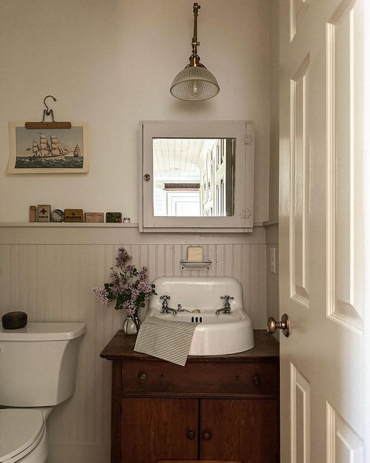 a white sink sitting under a mirror in a bathroom next to a toilet and vanity