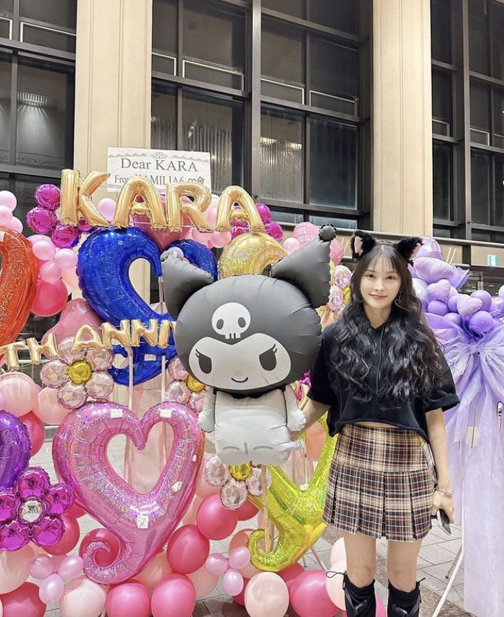 a woman standing in front of a display of balloons and character characters for an event