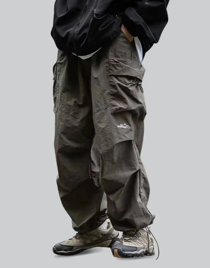 Green Parachute Pants Techwear Parachute Pants For Outdoor Activities, Techwear Baggy Parachute Pants For Outdoor, Baggy Techwear Parachute Pants For Outdoor, Techwear Pants With Pockets For Outdoor Activities, Techwear Parachute Pants With Functional Pockets For Outdoor Activities, Urban Style Baggy Bottoms For Outdoor Activities, Baggy Urban Bottoms For Outdoor Activities, Urban Style Baggy Parachute Pants For Outdoor, Baggy Cargo Pants For Winter Outdoor Use