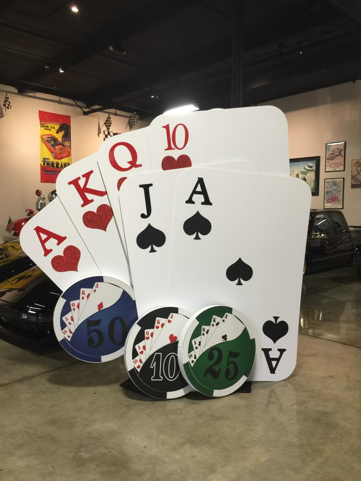 four playing cards sitting on top of each other in front of a black sports car