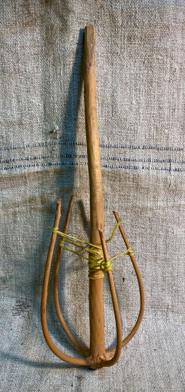 an old wooden stick with two handles and some string attached to it, sitting on a blue cloth