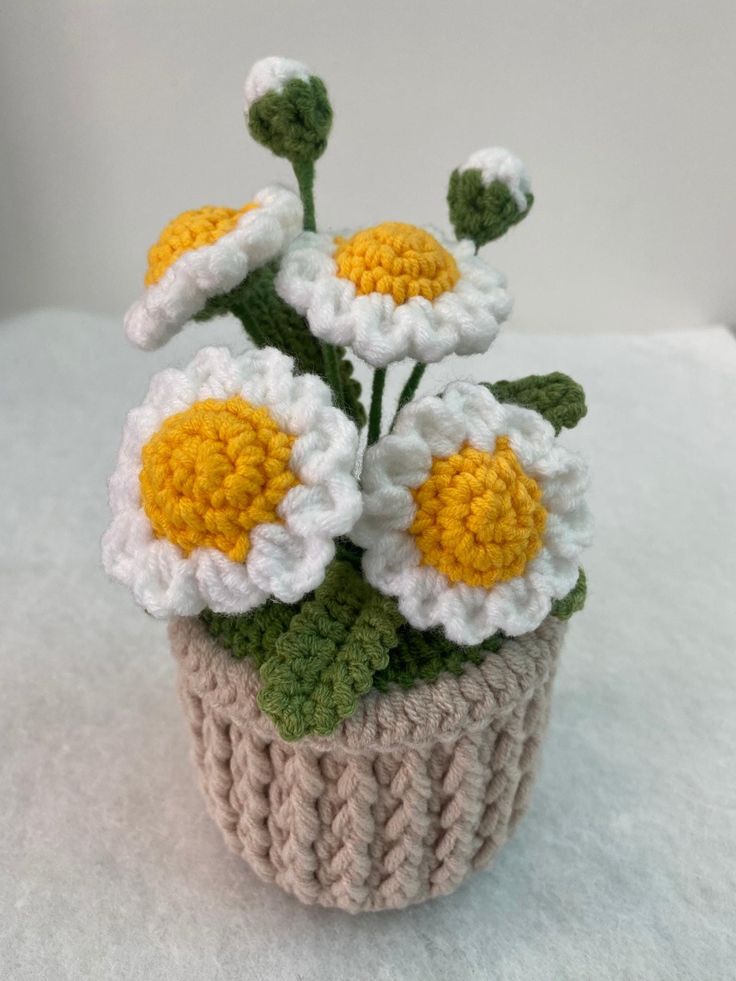 small crocheted flower pot with white and yellow flowers in it on a white surface