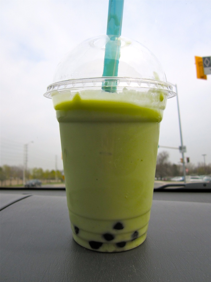 a green drink in a plastic cup with a blue straw