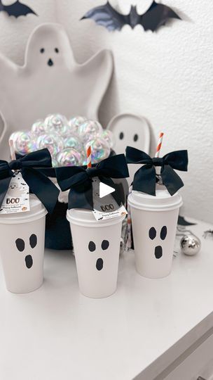 three cups with halloween decorations on them sitting on a table next to a white ghost