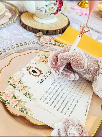 the table is set with pink and white flowers, lace doily, teacups, and other decorative items