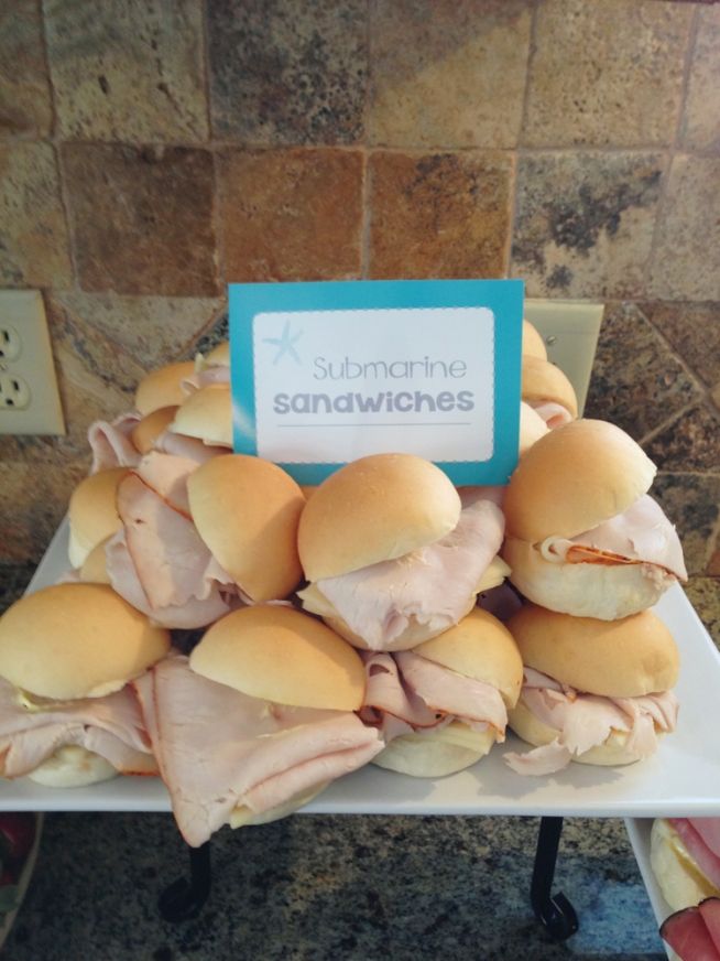 sandwiches are piled on top of each other with a sign in the middle that says submarine sandwiches