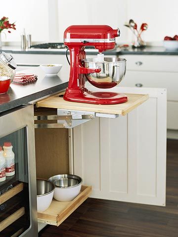 a red mixer sitting on top of a wooden stand in a kitchen next to an oven