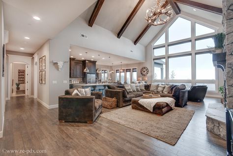 a living room filled with furniture next to a large open floor plan and lots of windows