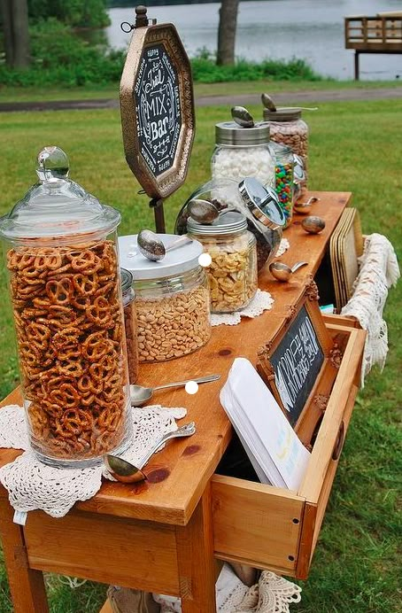 a wooden table topped with lots of different types of food and drink bottles on top of it