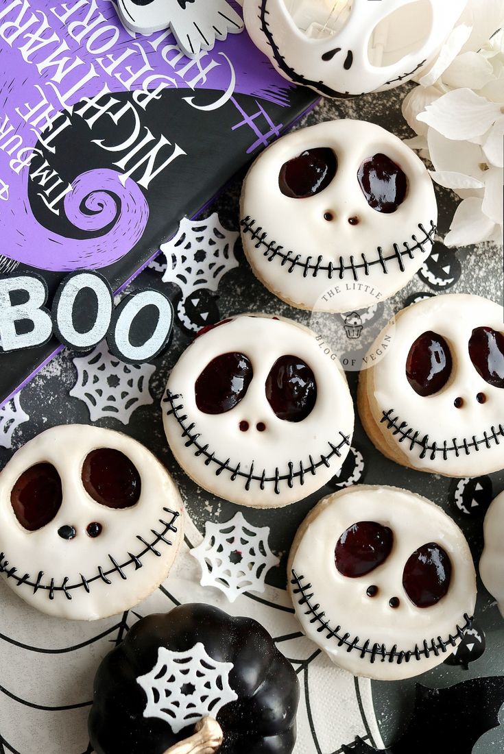 halloween cookies decorated with white frosting and black icing are arranged on a table