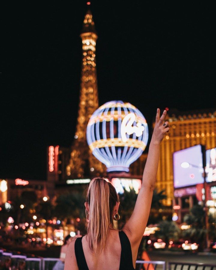 a woman standing in front of the eiffel tower at night with her arms up