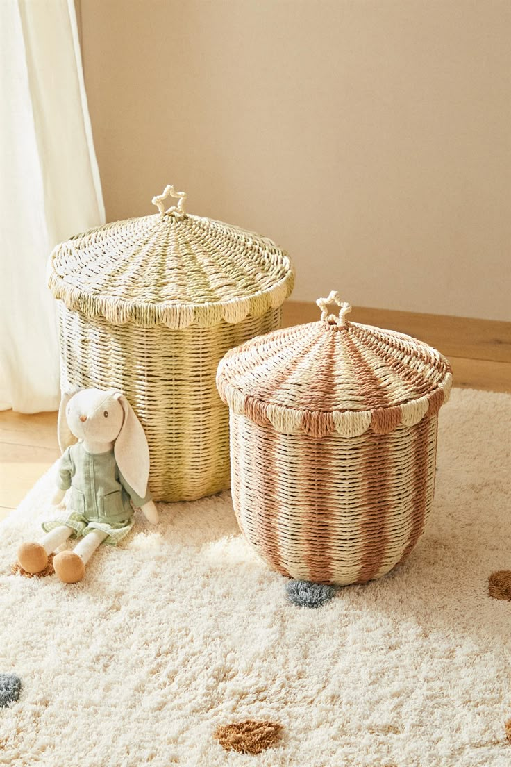 two wicker baskets sitting on top of a white rug next to a teddy bear