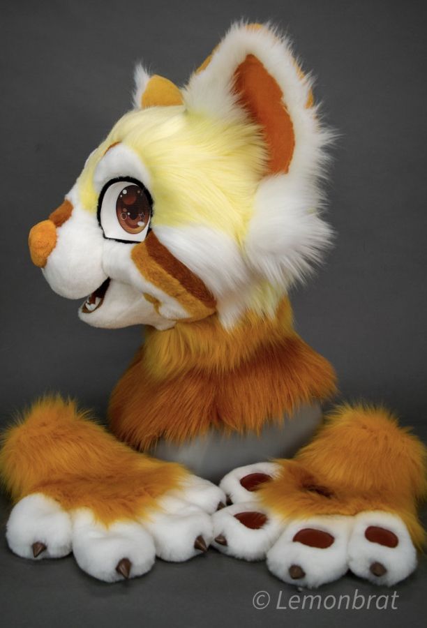 an orange and white stuffed animal sitting on top of a gray surface with its paws spread out