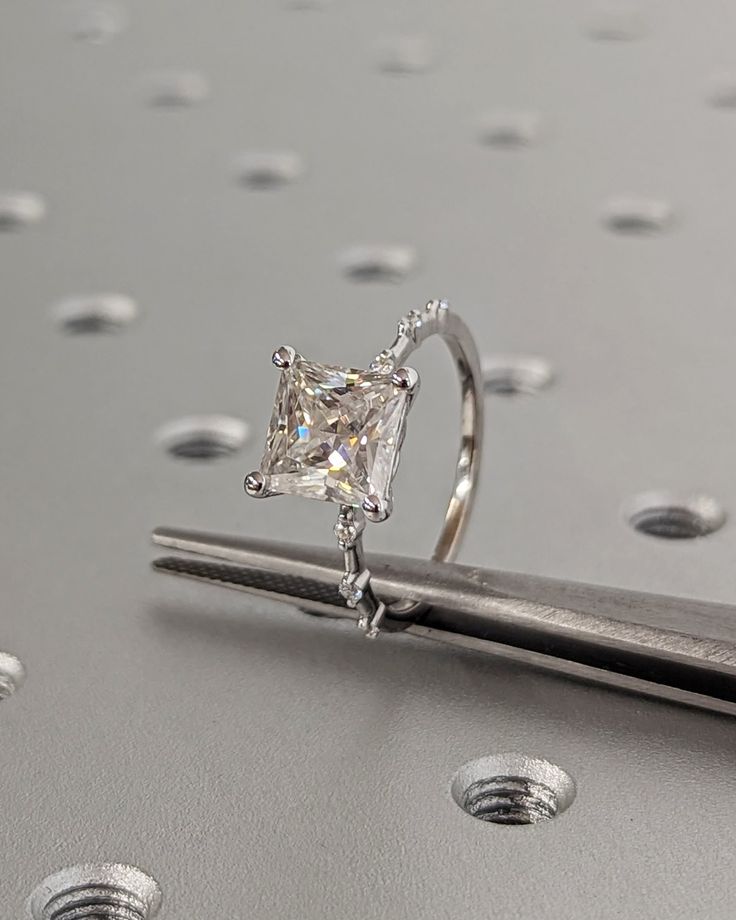 a diamond ring sitting on top of a piece of metal