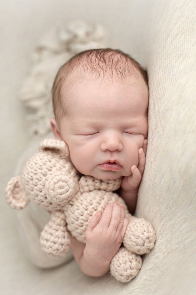 a newborn baby is holding a stuffed animal