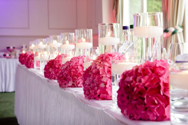 the table is set up with candles and pink flowers on it for a wedding reception