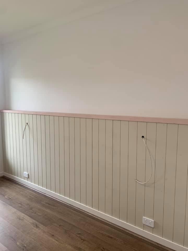 an empty room with wood flooring and white painted paneling on the wall behind it