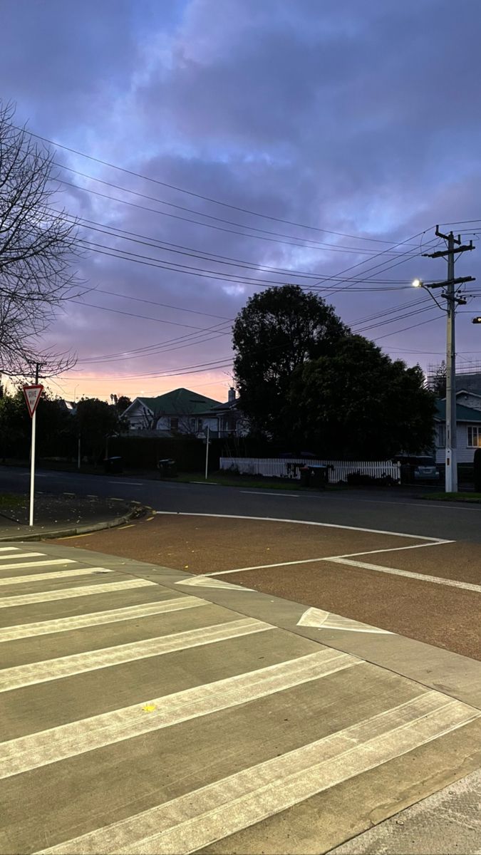 an empty parking lot with no cars on it at dusk or dawn, in front of some houses