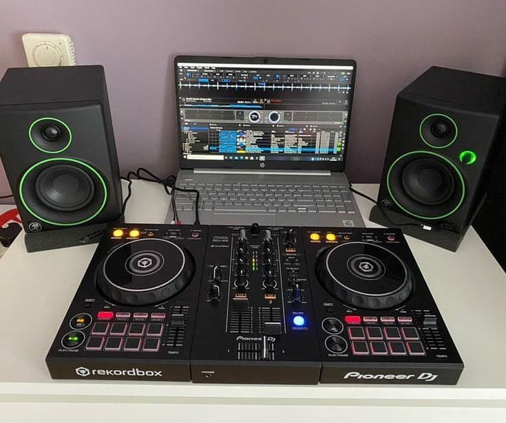 a laptop computer sitting on top of a desk next to two dj's and mixing equipment