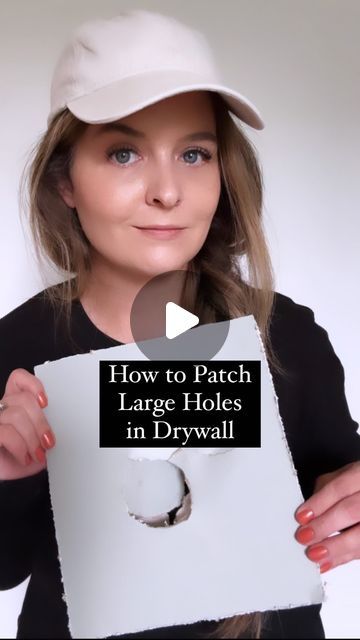 a woman holding up a hole in a piece of paper with the words how to patch large holes in drywall