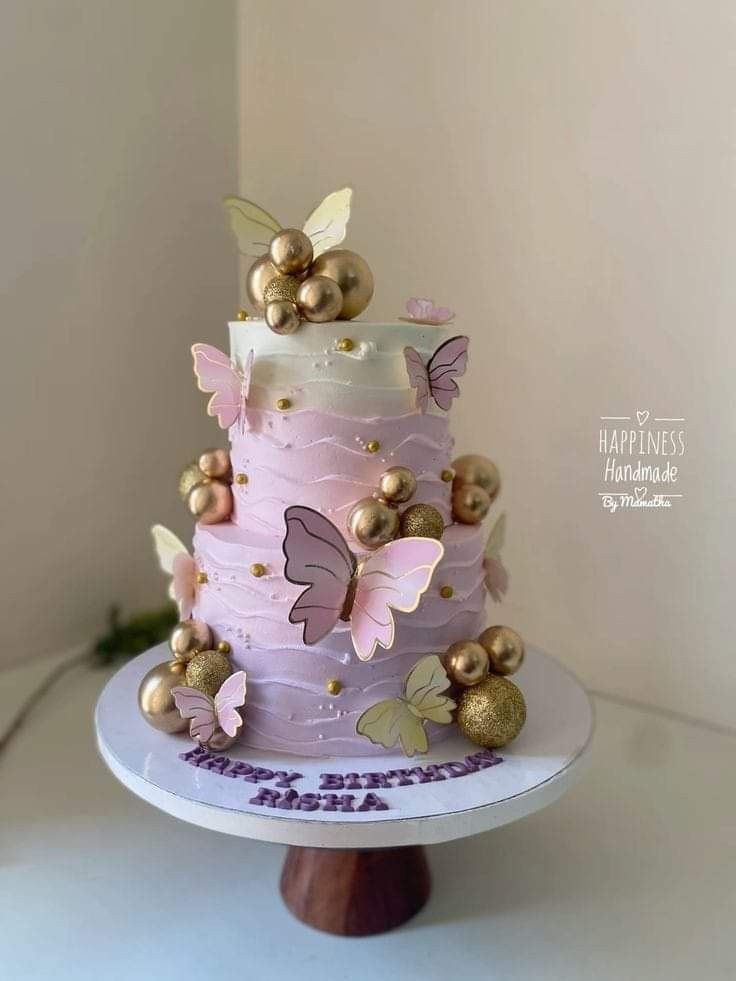 a three tiered cake with gold butterflies on top and purple frosting in the middle