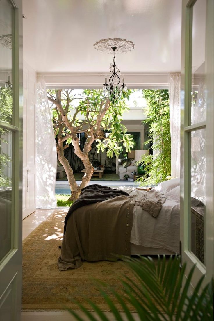 an open door leading to a bedroom with a tree in the corner and a chandelier hanging from the ceiling