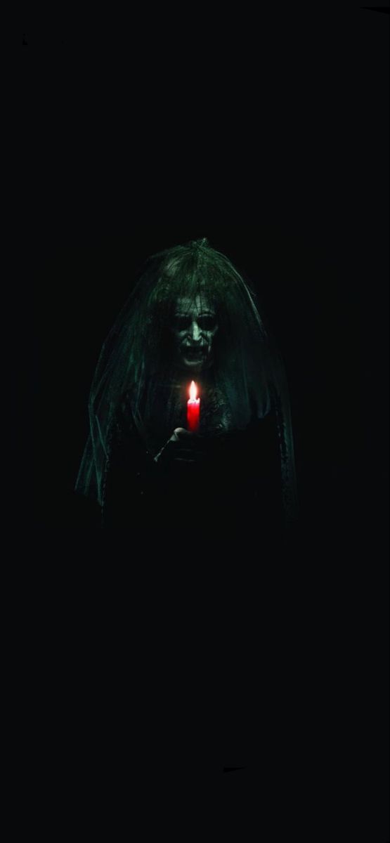 a creepy figure holding a lit candle in the dark with it's eyes open