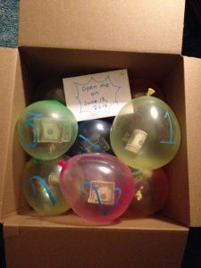 a box with some balloons in it and a sign on the top that says open one dollar