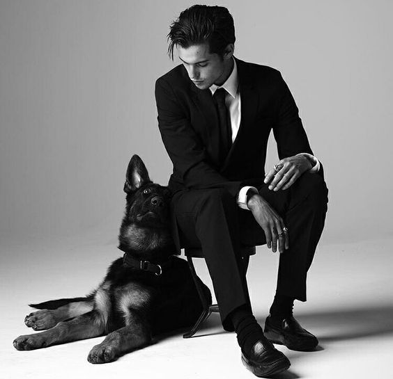 a man in a suit and tie sitting next to a dog