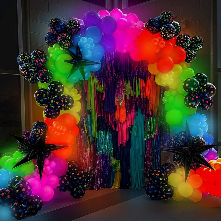 an assortment of balloons and streamers are displayed in front of a doorway at night