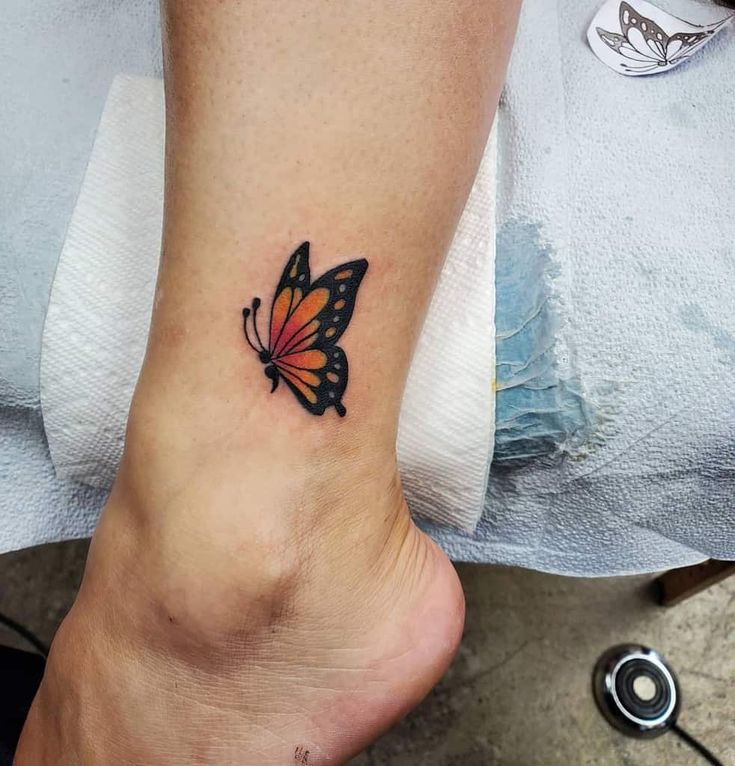 a woman's foot with a small butterfly tattoo on her left side calfocks