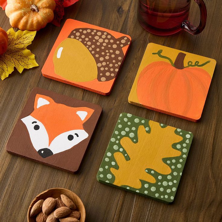 four coasters with different designs on them sitting on a table next to a bowl of nuts