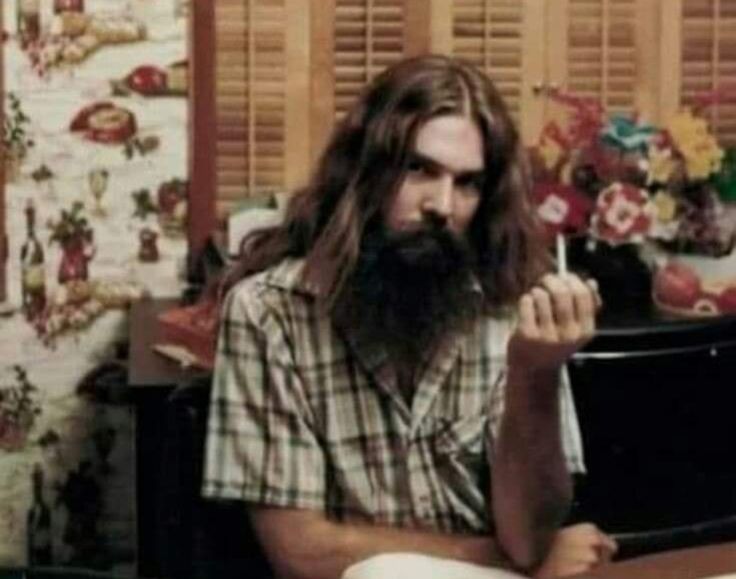 a man with long hair sitting at a desk