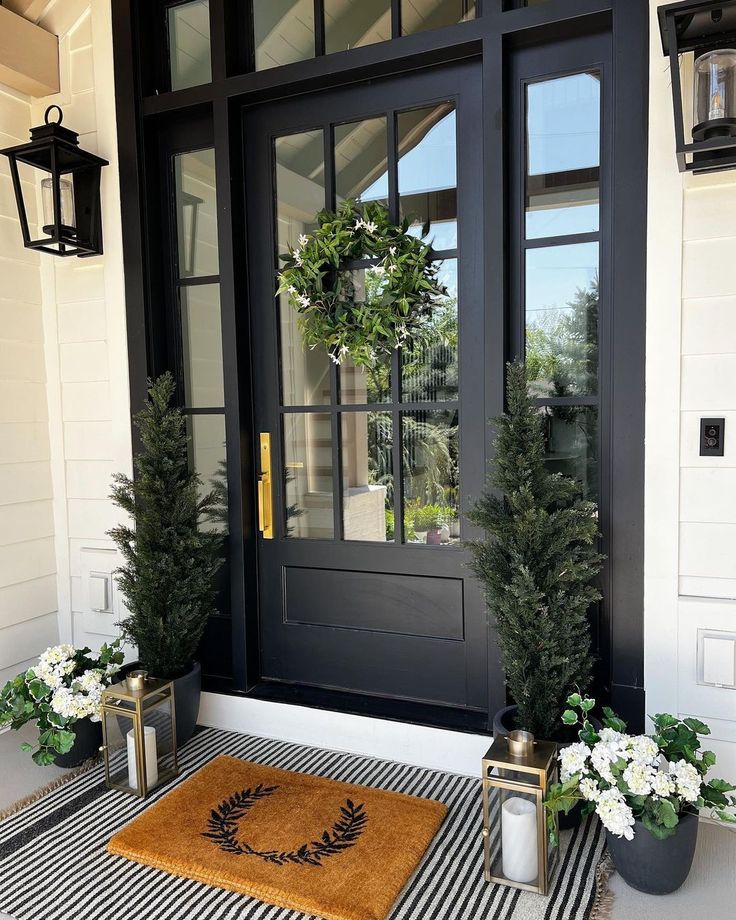 two potted plants are on the front porch with a welcome mat and doormat