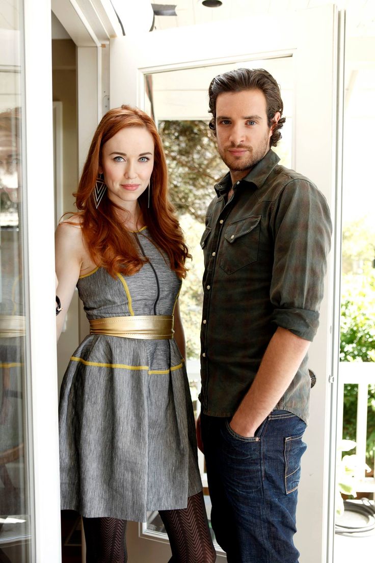 a man and woman standing next to each other in front of a glass door,