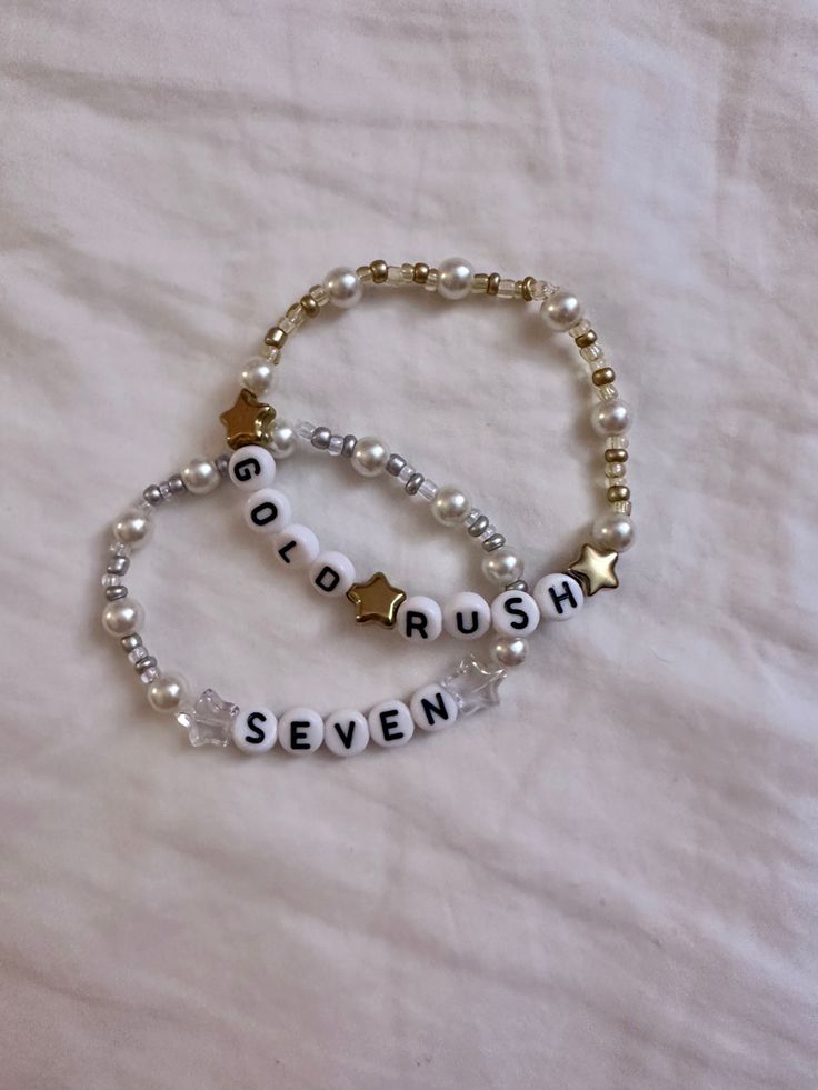 two beaded bracelets with words and stars are on a white sheeted surface