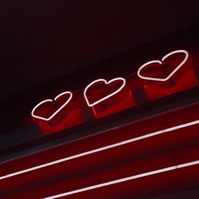 a neon sign with three hearts on it's side and the word love spelled in red