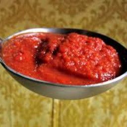 a spoon full of red sauce sitting on top of a table